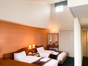 Een hotelkamer met twee bedden, een houten hoofdbord, bedlampen, een spiegel en een kledingkast.