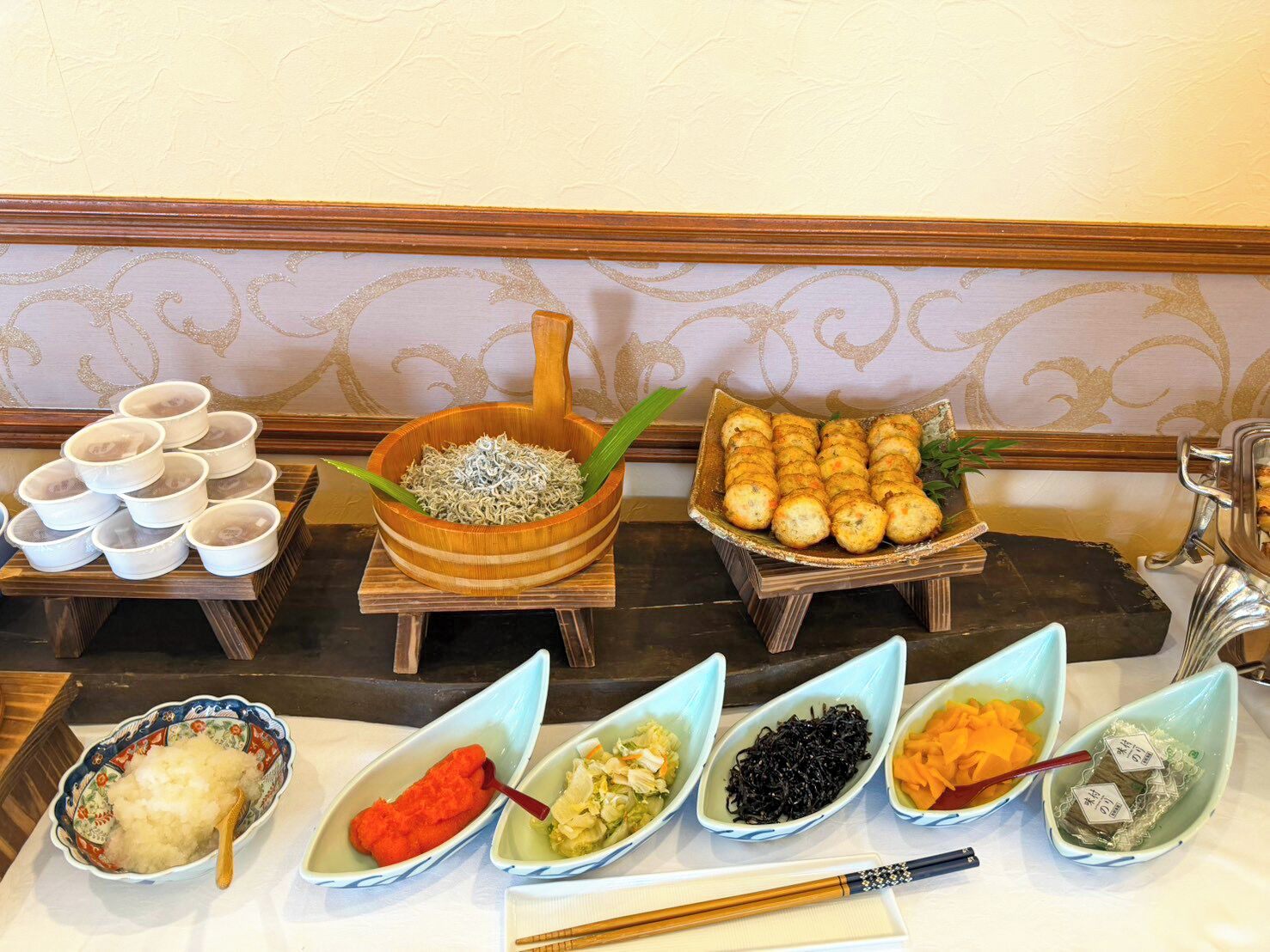 A buffet table with various dishes, including noodles, dumplings, and different types of sushi.