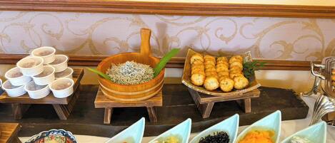 A buffet table with various dishes, including noodles, dumplings, and different types of sushi.