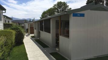 A row of single-story mobile homes with a 'BBQ' sign, a paved walkway, and a grassy area.