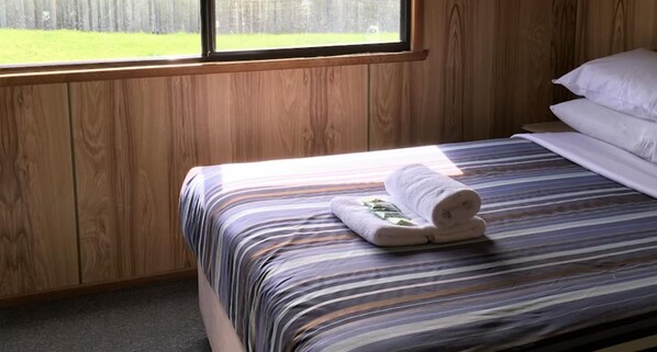 A bed with a striped bedspread and a rolled towel on it. - Discovery Parks - Mornington (Mornington)