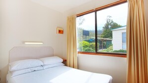 A single bed with white linens in a room with a large window. - Discovery Parks - Mornington (Mornington)