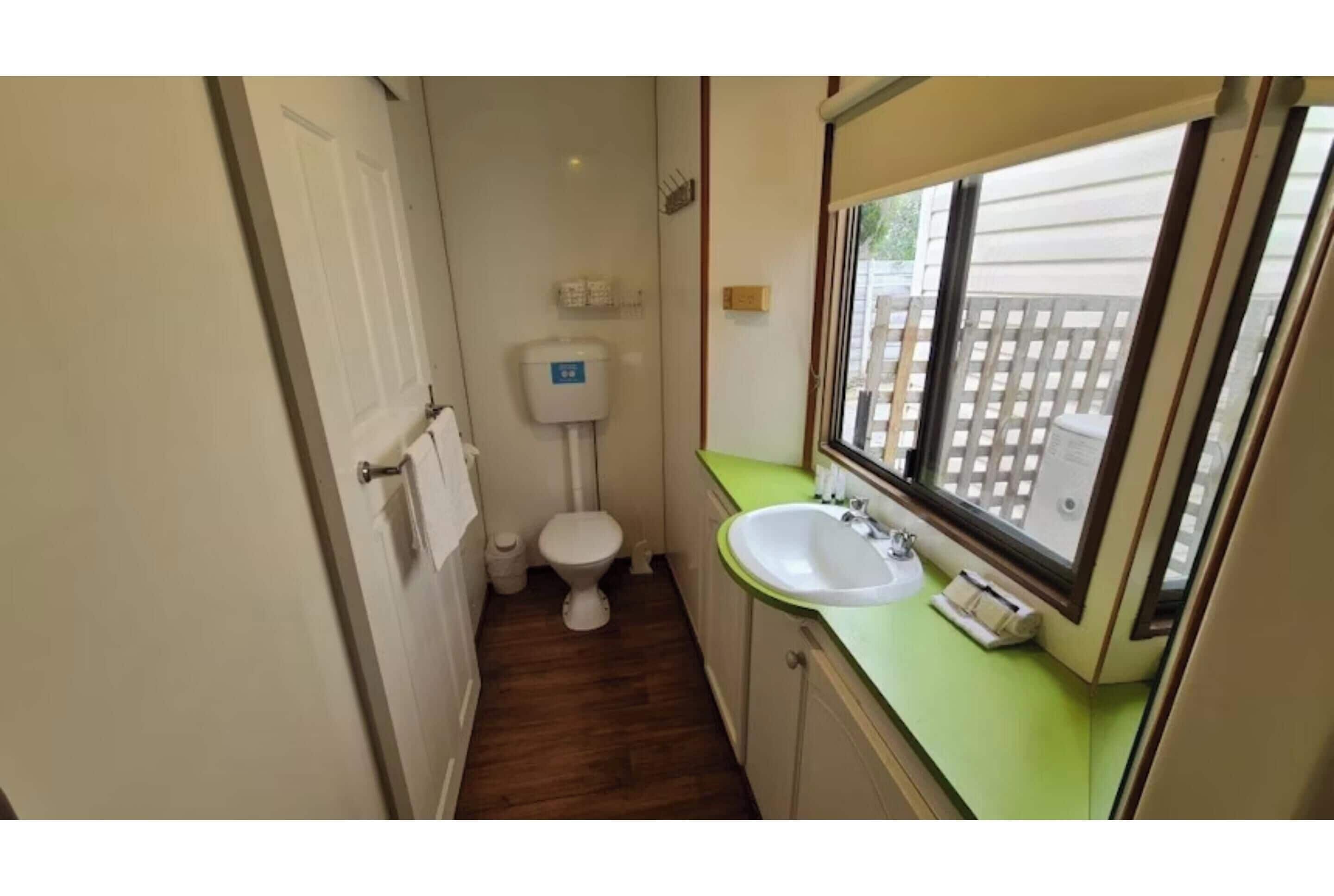 A small bathroom with a toilet, sink, and window.