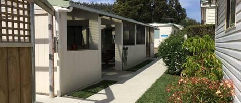 A row of mobile homes with a paved walkway and a small grassy area.
