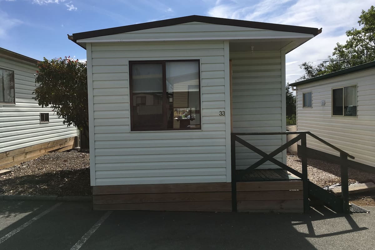 A small, single-story mobile home with a front porch and a window.
