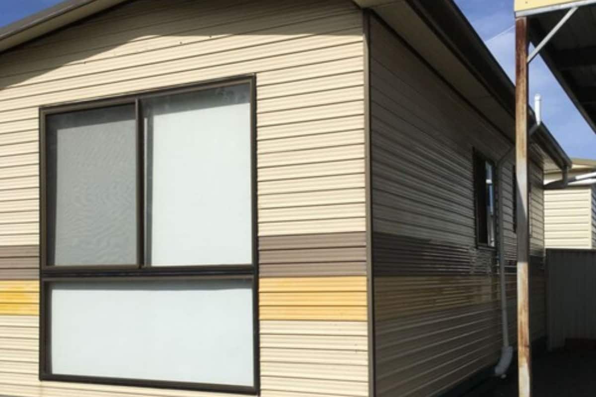 A mobile home with a large window, a door, and a visible garage door.