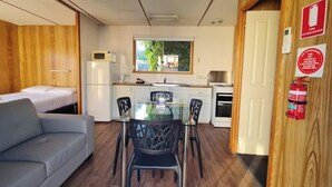 A compact room with a kitchenette, a dining table with chairs, a sofa, and a bed. - Discovery Parks - Mornington (Mornington)