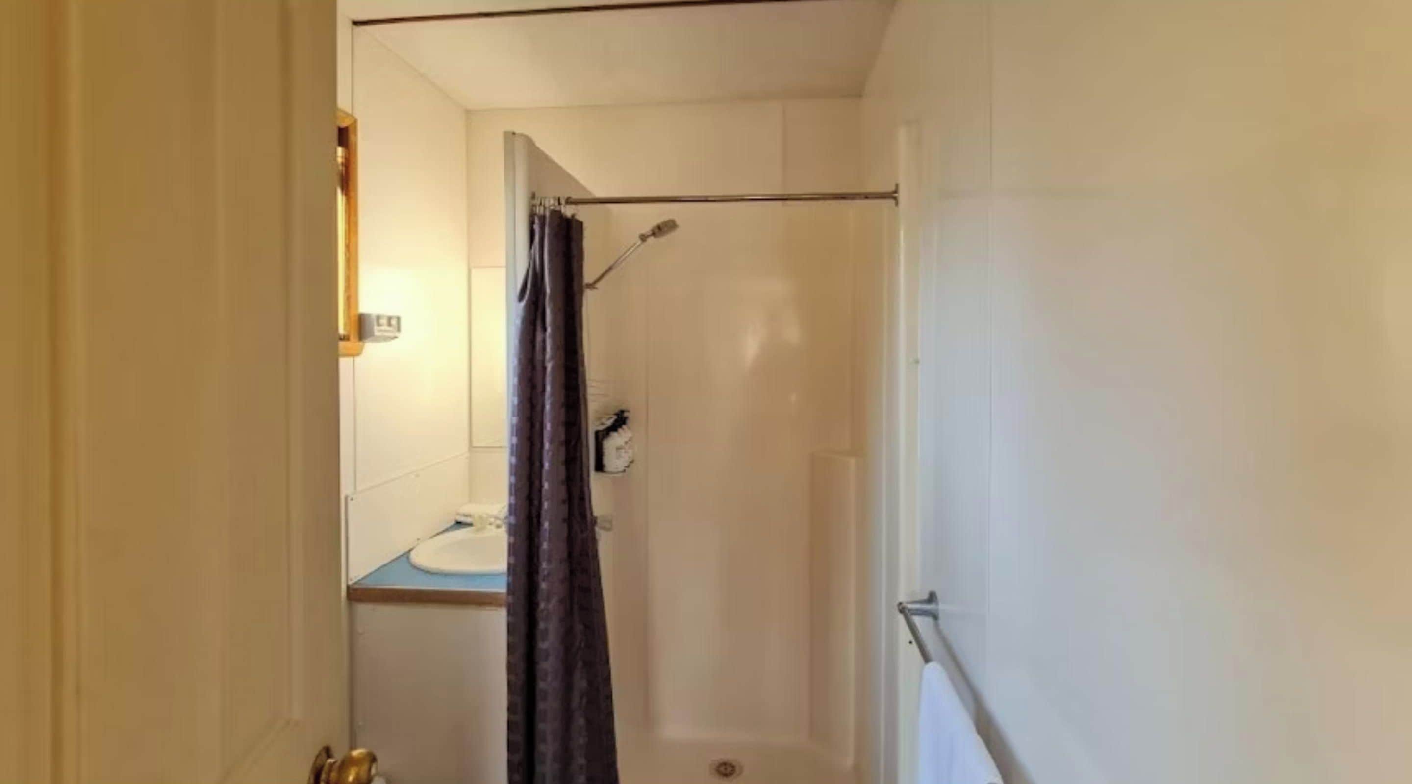 Un baño pequeño con ducha, inodoro y lavamanos.