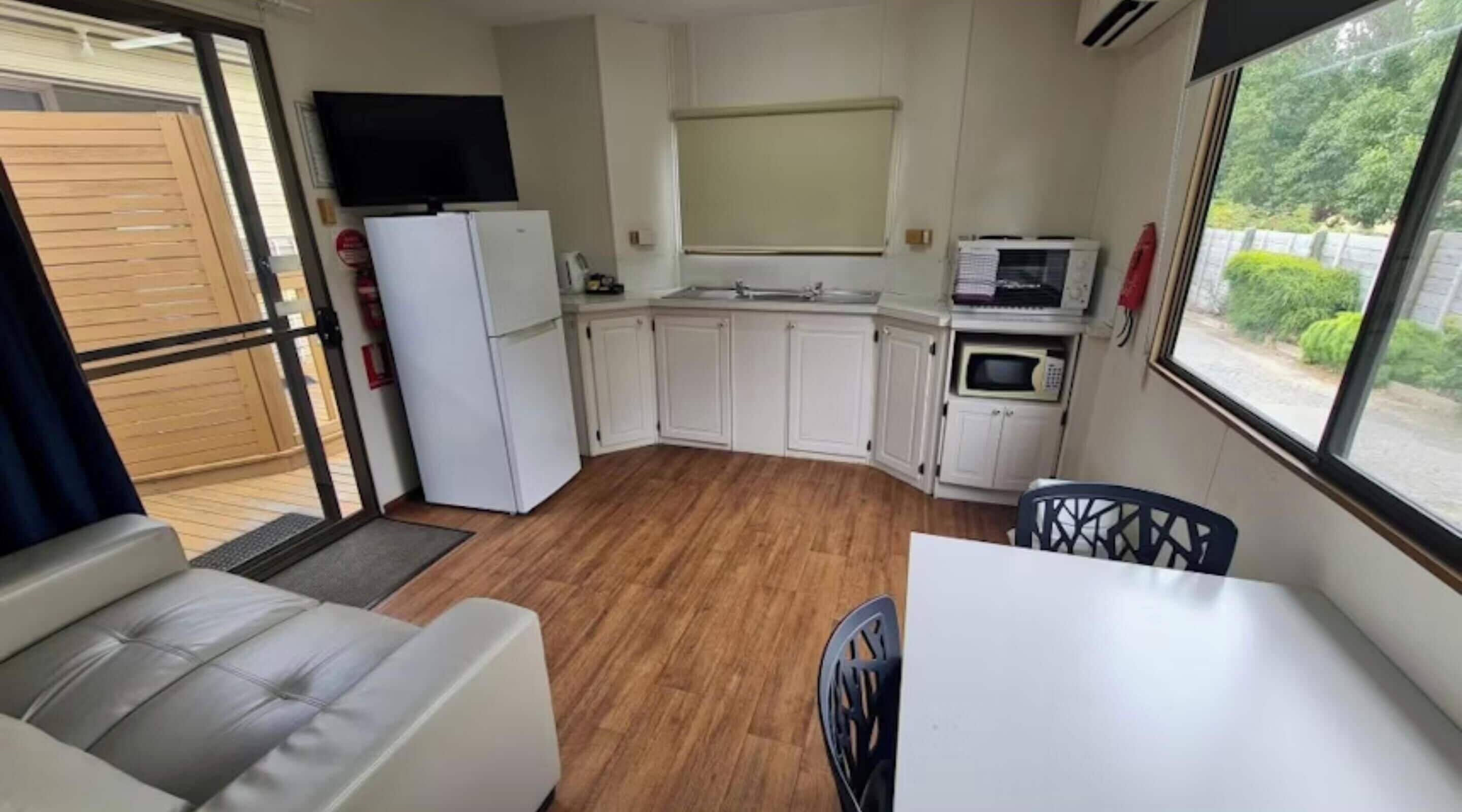 A compact kitchenette with a refrigerator, microwave, and a TV mounted above the counter.