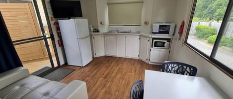 A compact kitchenette with a refrigerator, microwave, and a TV mounted above the counter.