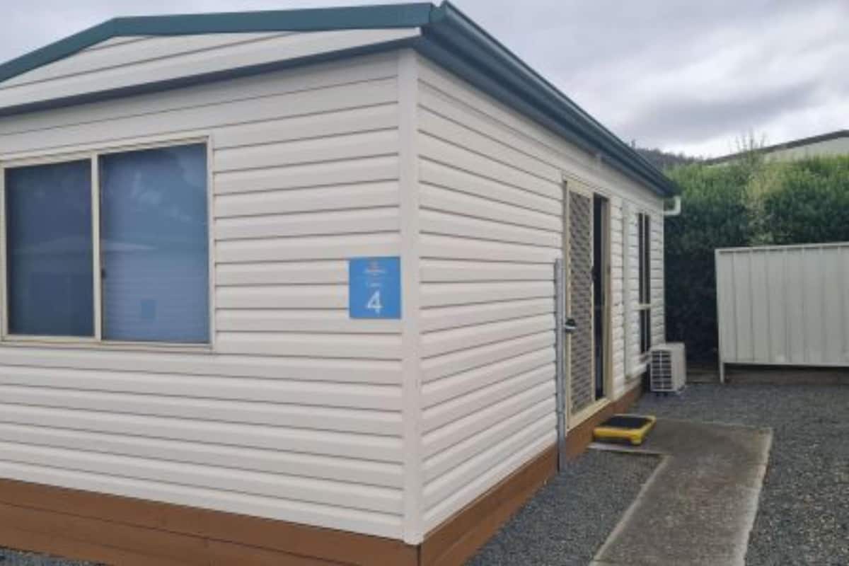 A single-story mobile home with a blue door, a window, and a number sign indicating room 4.