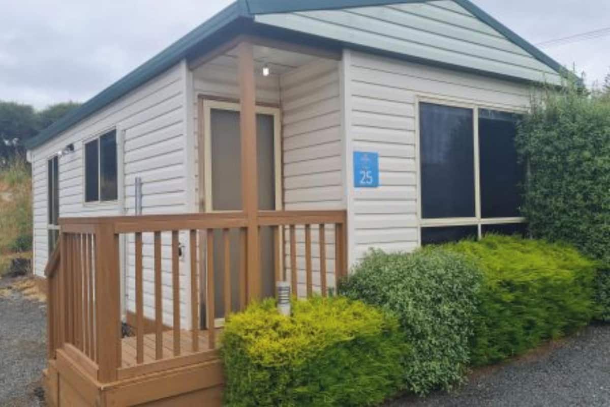 A single-story cabin with a wooden deck and a number '25' sign on the door.