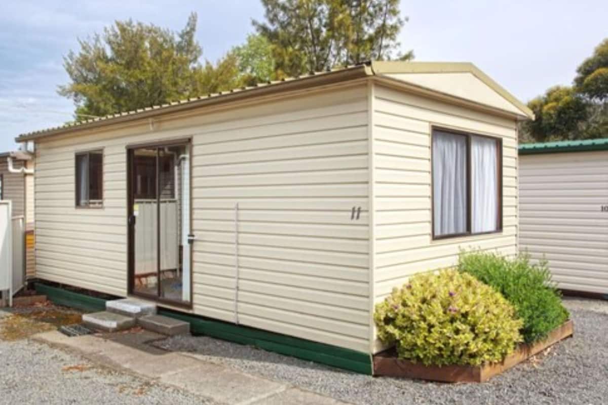 A single-story mobile home with a front door, a small porch, and a window.