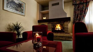 A cozy living room with a fireplace, red furniture, and a framed picture on the wall. - Residencia Daina (Arinsal)