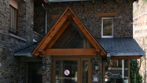 A stone building with a wooden front door and a small porch. - Residencia Daina (Arinsal)