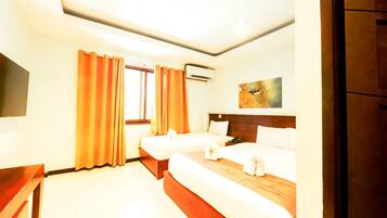 A hotel room with two beds, a flat-screen TV, an air conditioning unit, and a painting on the wall.