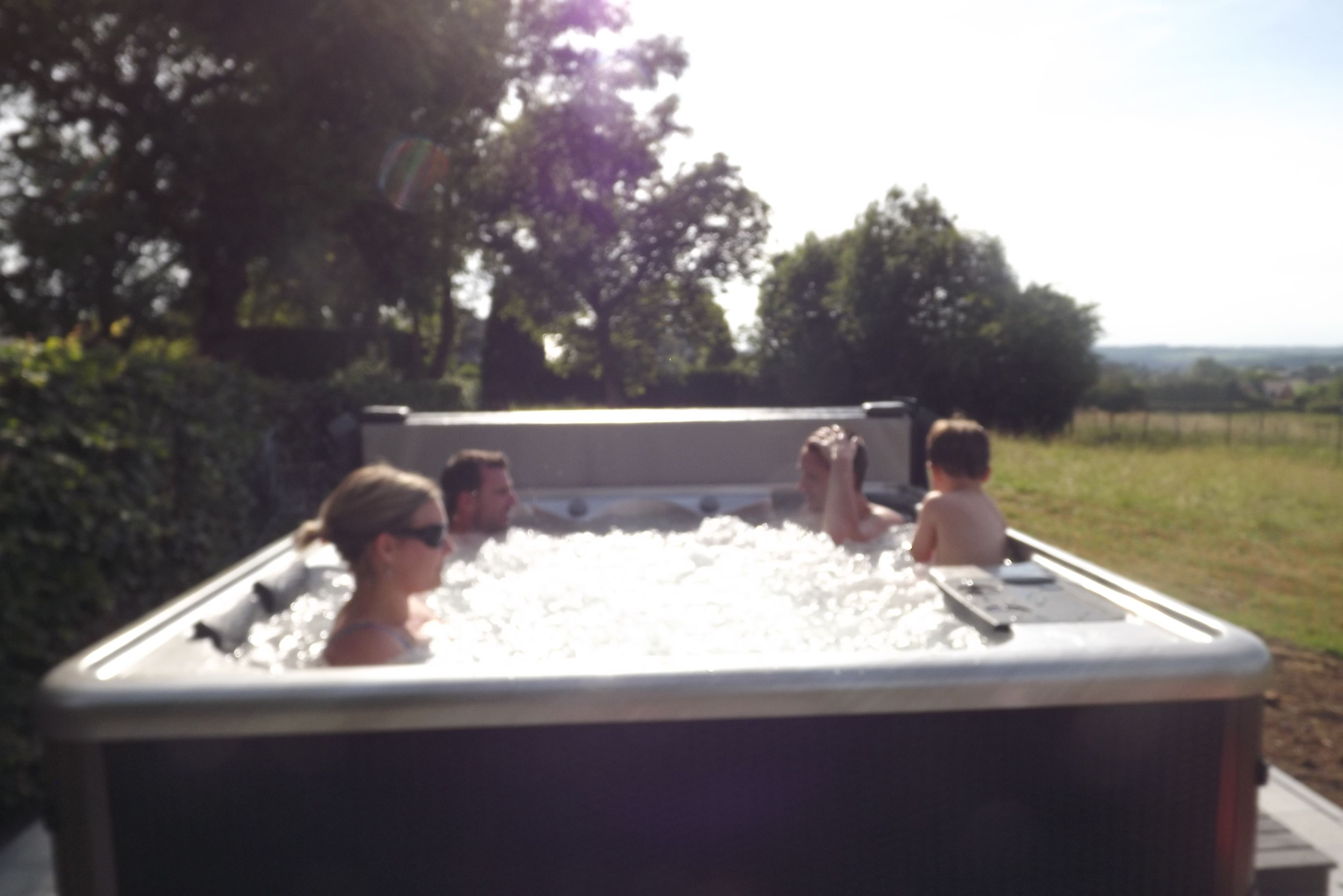 Een bubbelbad met mensen eromheen, omgeven door groen.