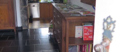 A kitchen with dark tiled flooring, a wooden cabinet, a sink, and a window.