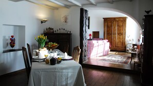 A dining area with a table set for a meal, a wooden cabinet, and a cozy seating area with a patterned rug. - La Buissonnière (Ferrieres)