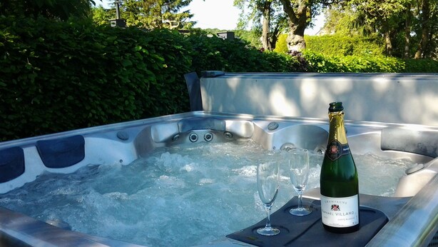 A hot tub with two glasses and a bottle of champagne. - La Buissonnière (Ferrieres)