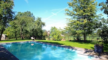 Una piscina al aire libre, sillones reclinables de piscina