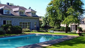 A stone house with a swimming pool, surrounded by lush greenery and trees. - La Buissonnière (Ferrieres)