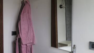 A bathroom with a white sink, a mirror, and a towel rack with a pink towel.