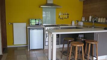 A modern kitchen with a central island, stainless steel appliances, and a yellow accent wall.