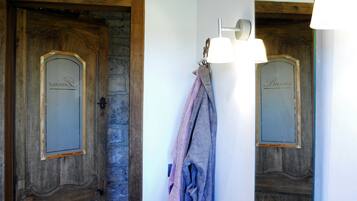 Dos puertas de madera con paneles de vidrio, una toalla colgada en un perchero de pared, y una lámpara sobre el perchero.