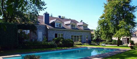 Een buitenzwembad, ligstoelen bij het zwembad