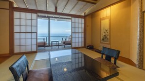 A traditional Japanese room with tatami flooring, a low table, and a view of the sea. - Kissho CAREN (Higashiizu)