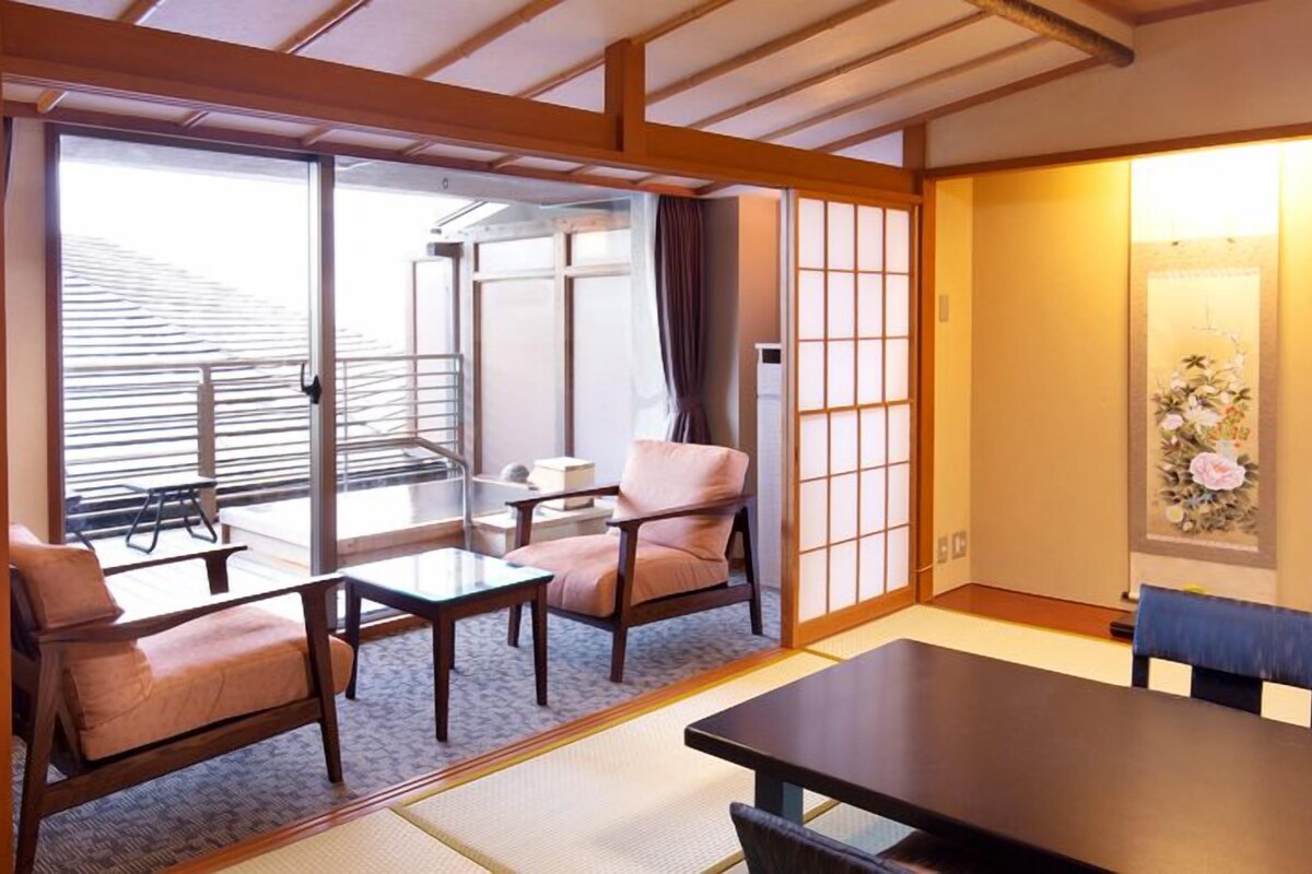 A traditional Japanese-style room with tatami flooring, a low table, and seating.