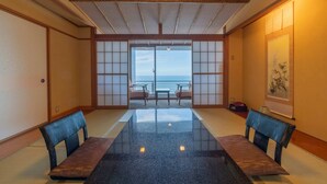 A traditional Japanese room with tatami flooring, a low table, and a view of the sea. - Kissho CAREN (Higashiizu)
