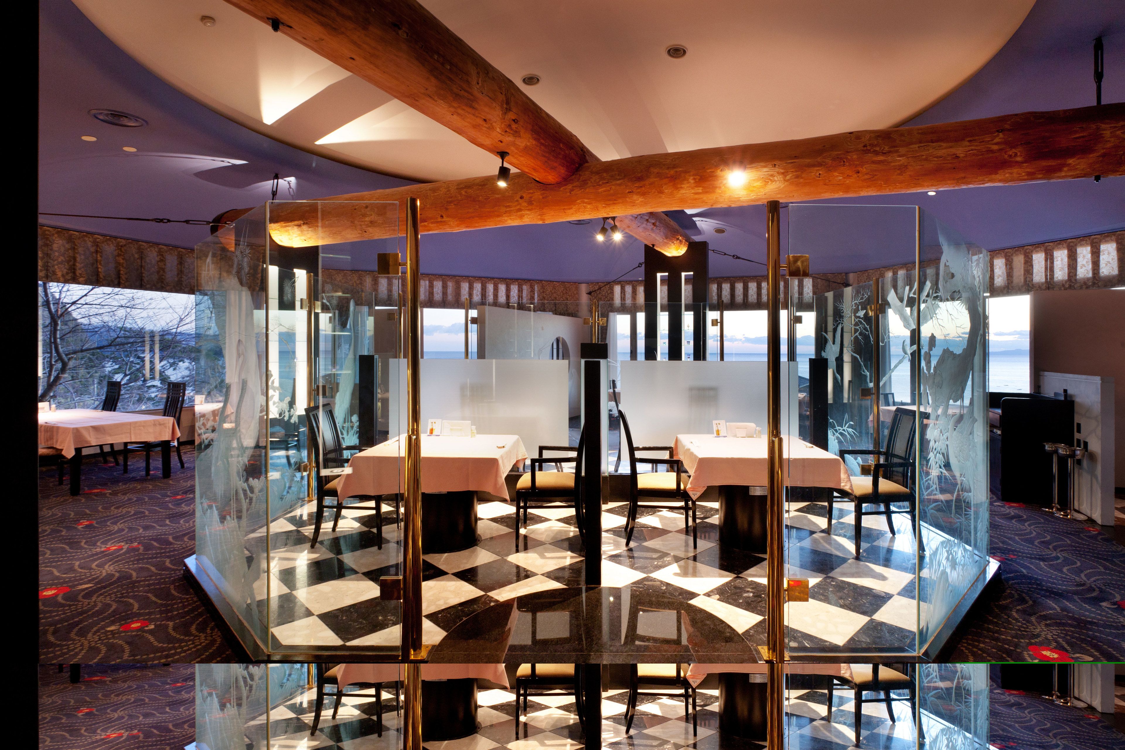 Un restaurante con piso a cuadros, separaciones de vidrio y mesas con sillas.