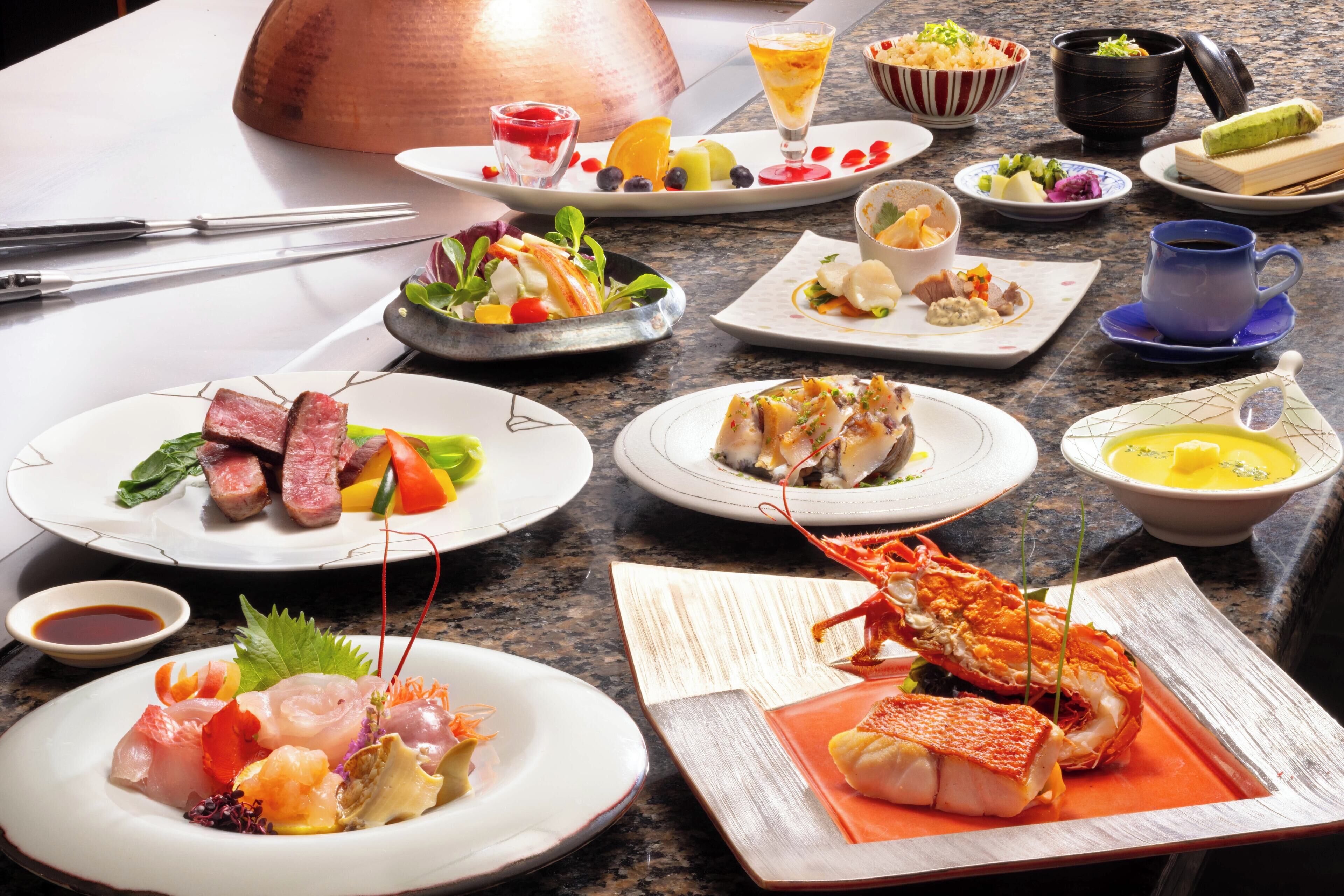 Diversos pratos em uma mesa, incluindo frutos do mar, legumes e um lagosto.