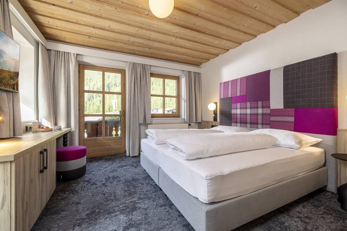 Un dormitorio con una cama grande, un escritorio y una ventana con cortinas.