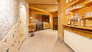 A wooden interior with a tiled floor, a reception desk, and a wall with shelves holding jars. - Kinder- & Gletscherhotel Hintertuxerhof (Tux)