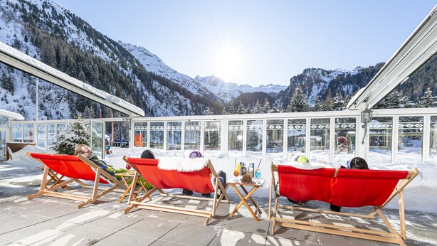 A snow-covered outdoor seating area with red chairs and tables, overlooking a mountainous landscape. - Kinder- & Gletscherhotel Hintertuxerhof (Tux)
