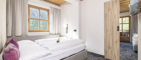 A modern bedroom with a bed, a window, and a wooden ceiling.