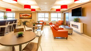 Un moderno vestíbulo de hotel con una zona de bar, disposiciones para sentarse y un televisor montado en la pared.