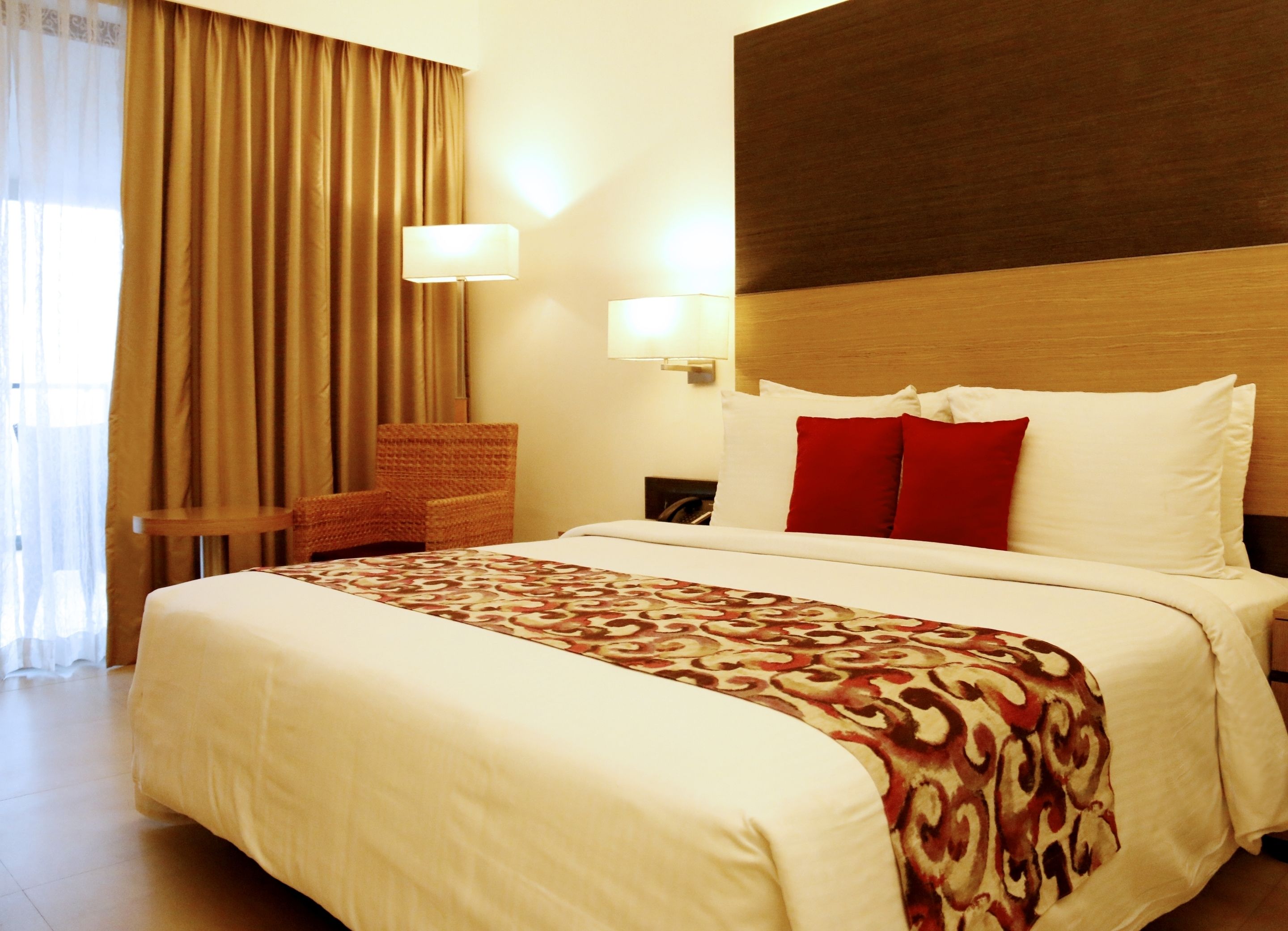 Une chambre d’hôtel avec un grand lit, une chaise, une lampe et une vue sur l’extérieur.