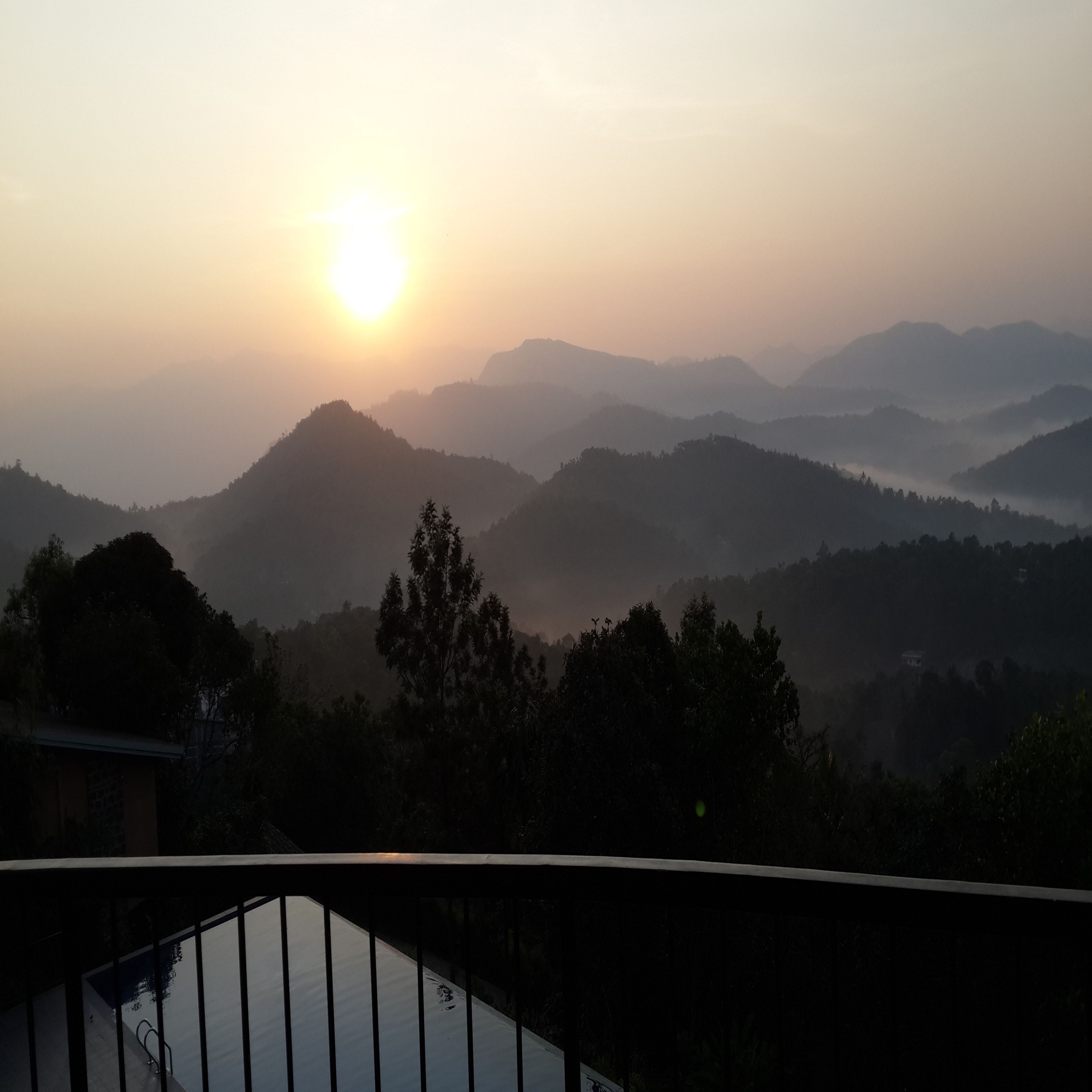 Amanecer sobre un paisaje montañoso con un edificio en primer plano.