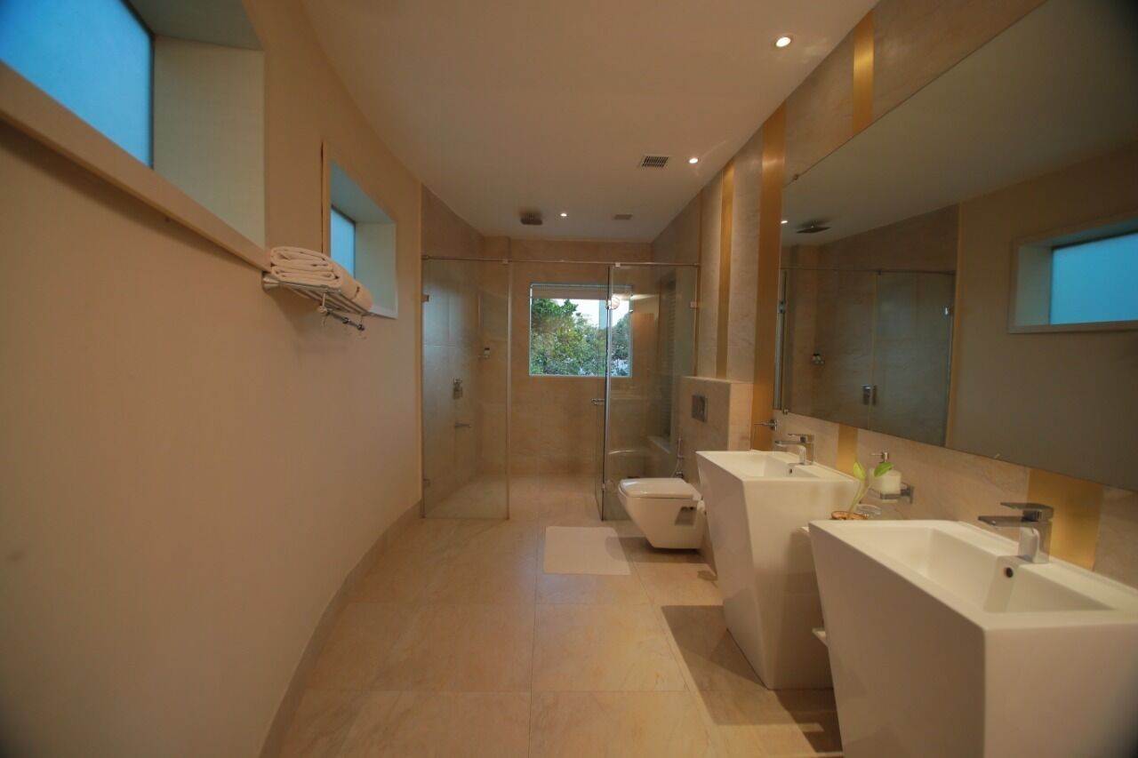 Un baño moderno con cabina de ducha de vidrio, inodoro y dos lavamanos.