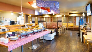 Zona de buffet amb diverses estacions de menjar, una barra de fusta i una zona de seients amb taules i cadires.