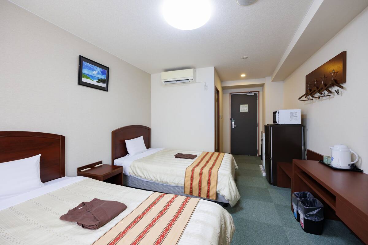Habitació d'hotel amb dos llits, un refrigerador, una cafetera i un safataire.