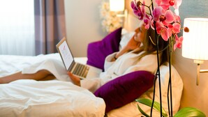 A hotel room with a bed, a laptop, a purple pillow, and a flower arrangement. - 24hours Apartment Hotel (Vienna)