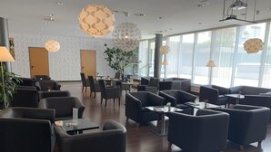 A modern hotel lobby with dark leather sofas, wooden tables, and a large potted plant. - 24hours Apartment Hotel (Vienna)