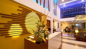 A modern hotel lobby with a reception desk, a large vase of flowers, and a high ceiling with blue lighting. - The Ocean Colombo (Colombo)