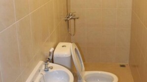 A small, tiled bathroom with a toilet, bidet, and sink. - De Orange Pasteur Guest House by HouseinBandung (Bandung)