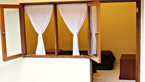 A room with a bed, a wooden cabinet, and a window with white curtains. - De Orange Pasteur Guest House by HouseinBandung (Bandung)